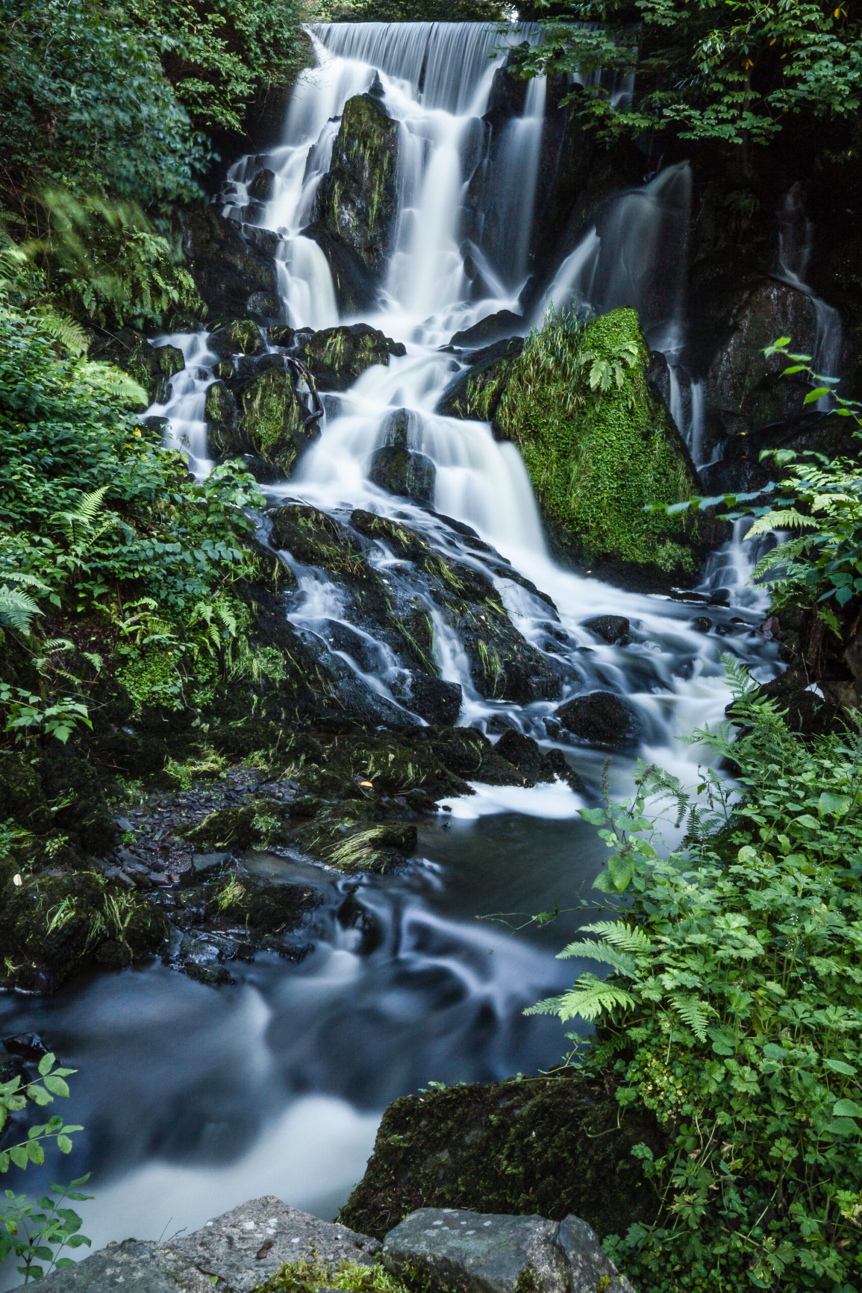 Long-exposure photograph of Crawfordsburn Waterfall cascading over moss-covered rocks in County Down, Northern Ireland.