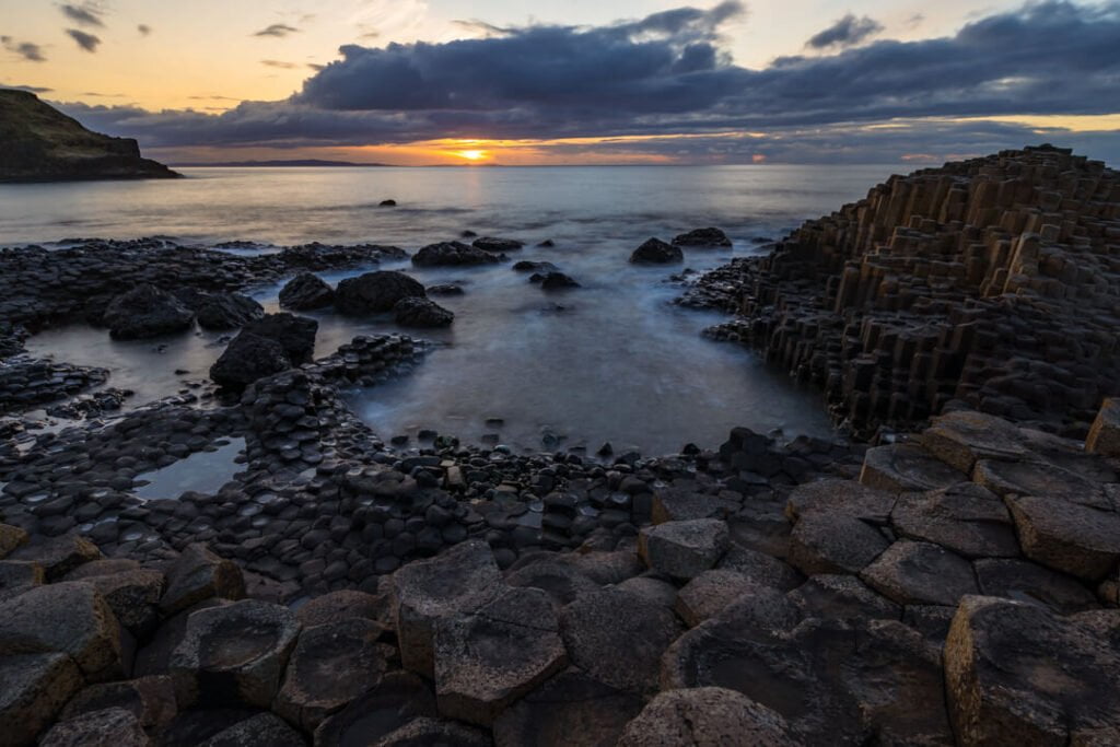 Sunset over the Giant’s Causeway basalt columns with long-exposure water on the Causeway Coast, Northern Ireland